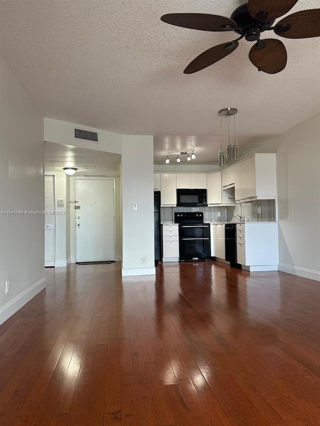 unfurnished living room with a textured ceiling, dark wood-type flooring, ceiling fan, and sink