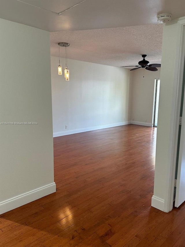 spare room with a textured ceiling, ceiling fan, and dark hardwood / wood-style flooring