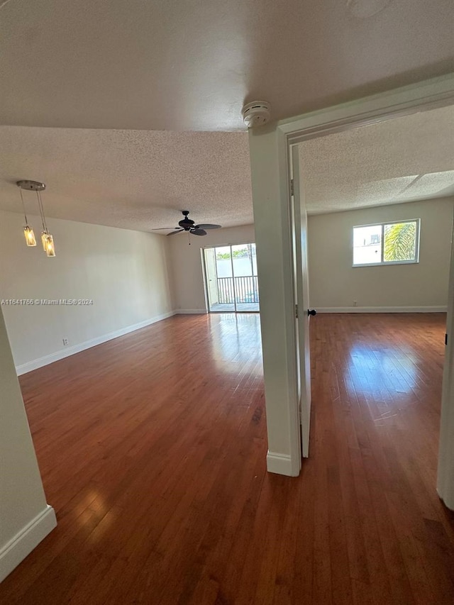 empty room featuring a textured ceiling, dark wood-type flooring, and ceiling fan