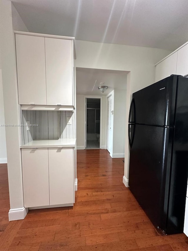 kitchen featuring black refrigerator, wood-type flooring, and white cabinetry