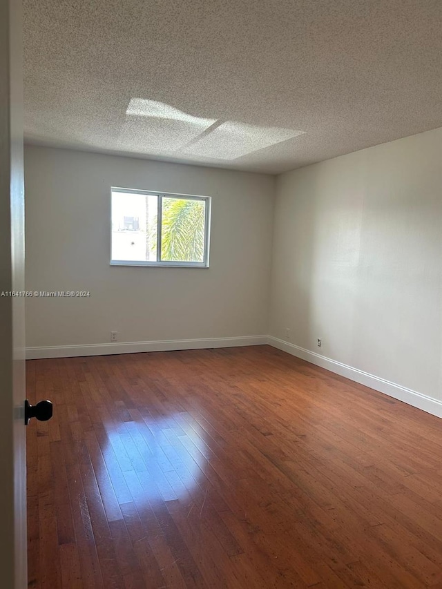 unfurnished room with a textured ceiling and dark hardwood / wood-style floors