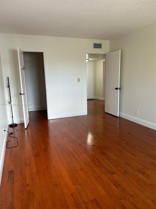 spare room with a textured ceiling and dark wood-type flooring