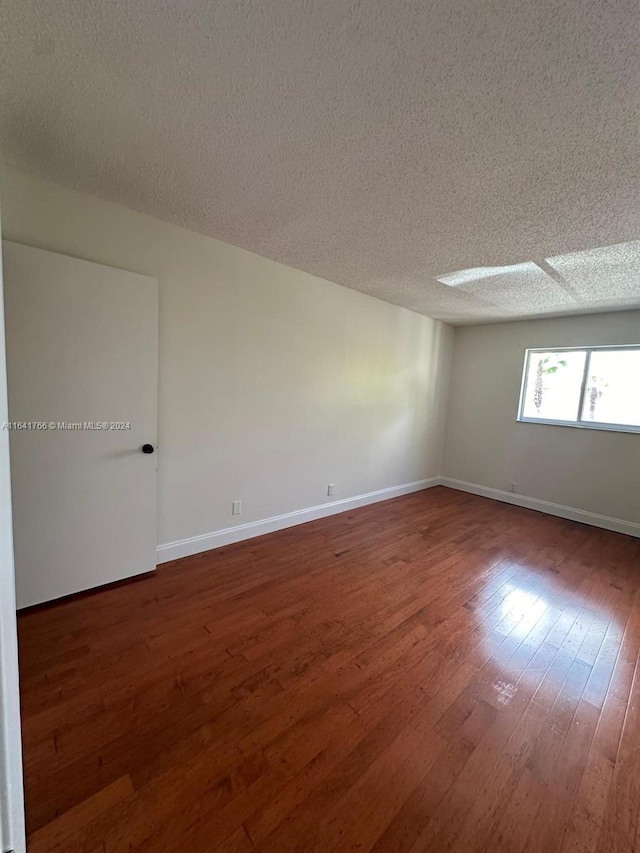 spare room featuring dark hardwood / wood-style flooring and a textured ceiling