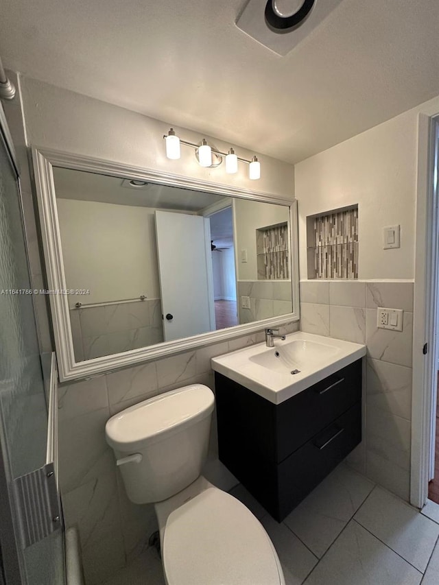 bathroom featuring tile walls, walk in shower, toilet, and vanity