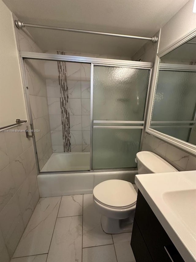 full bathroom featuring toilet, bath / shower combo with glass door, and vanity