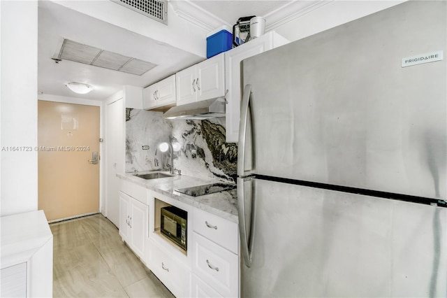 kitchen featuring light stone countertops, under cabinet range hood, black appliances, white cabinetry, and a sink