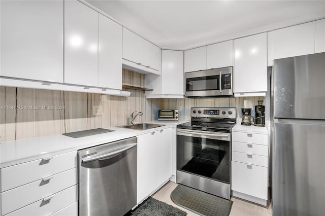 kitchen featuring tasteful backsplash, sink, stainless steel appliances, and white cabinetry