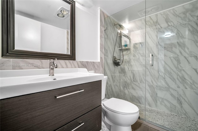 bathroom with an enclosed shower, vanity, tile walls, and toilet