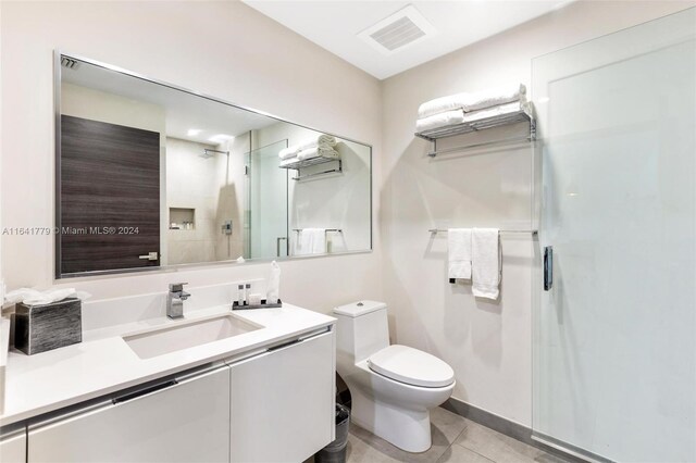 bathroom with tile patterned flooring, vanity, toilet, and walk in shower