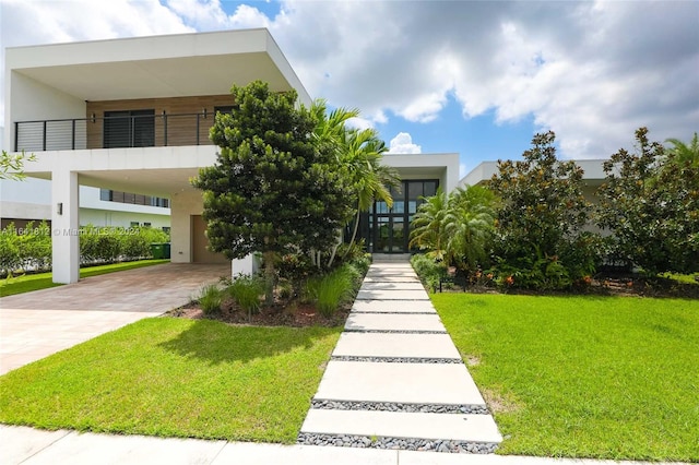 view of front of home featuring a balcony, a carport, and a front yard