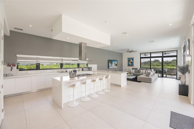 kitchen featuring ceiling fan, white cabinets, a kitchen island, and a healthy amount of sunlight