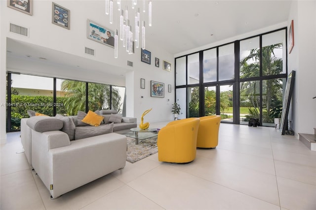 living room featuring a chandelier, light tile patterned floors, and a towering ceiling