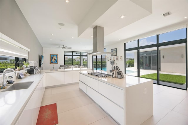 kitchen with sink, island exhaust hood, white cabinetry, and light tile patterned floors