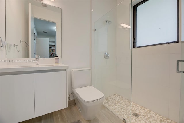 bathroom with wood-type flooring, toilet, walk in shower, and vanity