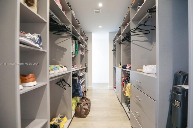 walk in closet with light hardwood / wood-style flooring