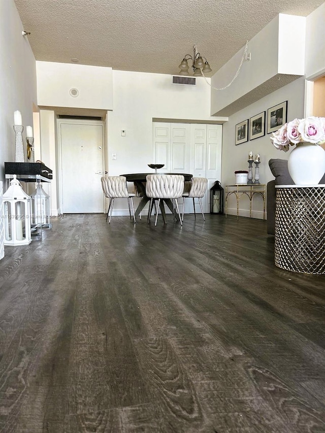 dining area featuring baseboards, a textured ceiling, visible vents, and wood finished floors