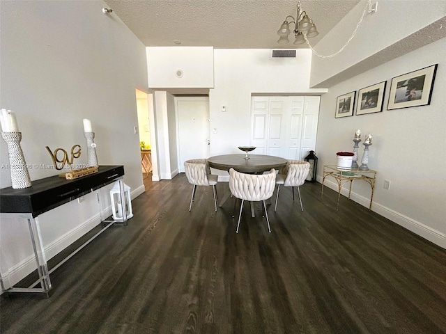 dining area with a textured ceiling, wood finished floors, visible vents, baseboards, and an inviting chandelier