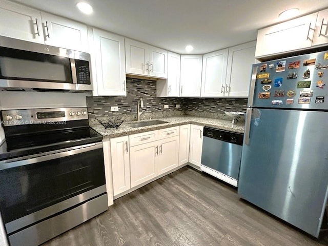 kitchen with stainless steel appliances, a sink, white cabinets, tasteful backsplash, and dark wood finished floors