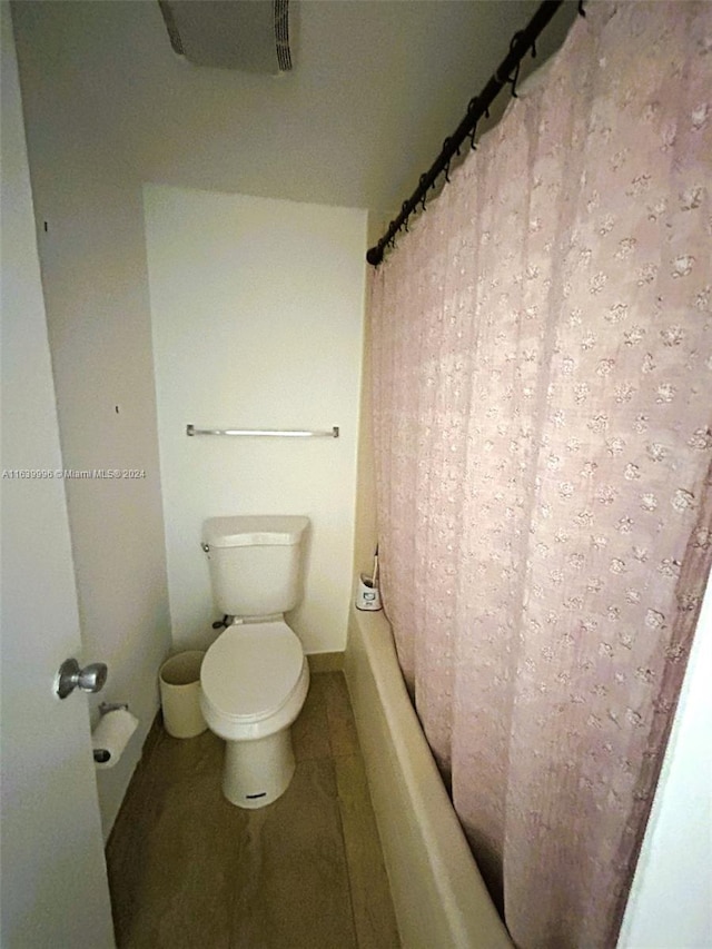 bathroom featuring toilet and shower / bathtub combination with curtain