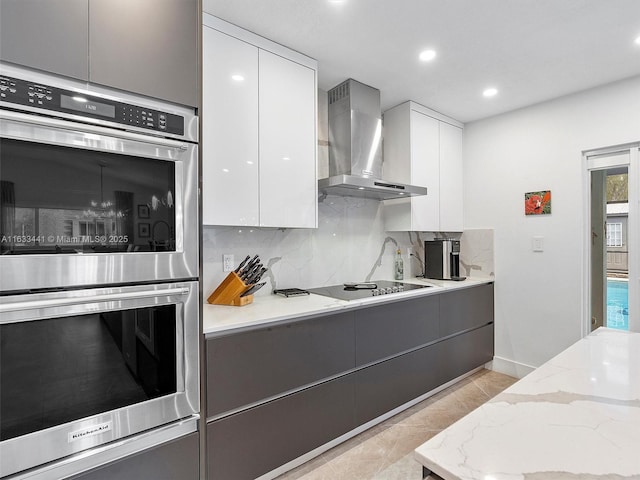 kitchen with wall chimney exhaust hood, stainless steel double oven, modern cabinets, and gray cabinetry