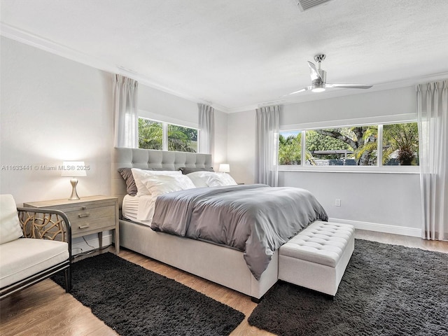 bedroom featuring ornamental molding, multiple windows, and wood finished floors