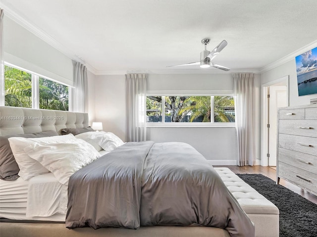 bedroom featuring ceiling fan, multiple windows, crown molding, and wood finished floors