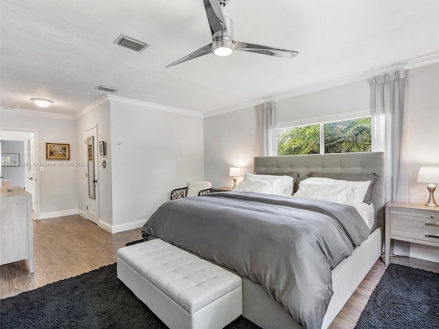 bedroom featuring light wood finished floors, visible vents, baseboards, a ceiling fan, and ornamental molding