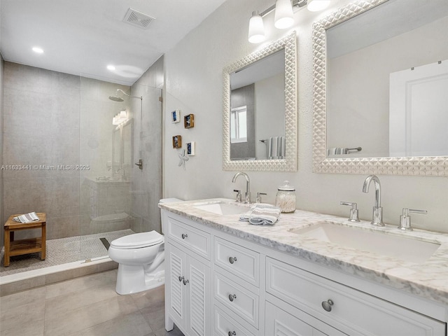 bathroom featuring visible vents, a sink, a tile shower, and toilet