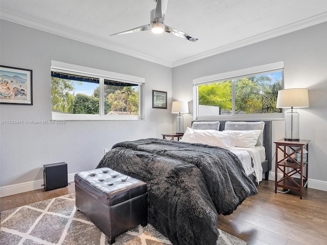 bedroom with multiple windows, baseboards, crown molding, and wood finished floors