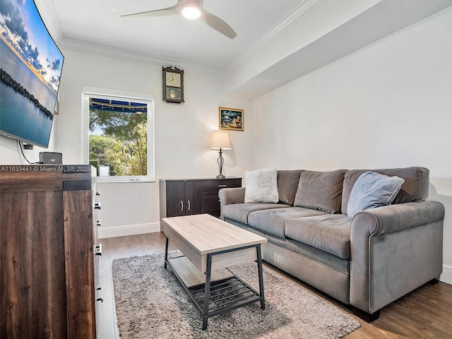 living area with ornamental molding, ceiling fan, baseboards, and wood finished floors