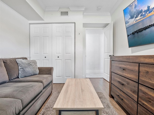 living area featuring visible vents, wood finished floors, and ornamental molding