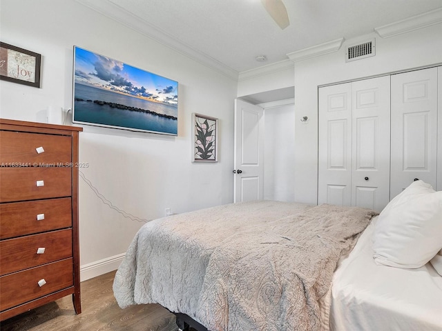 bedroom with visible vents, a ceiling fan, ornamental molding, wood finished floors, and a closet