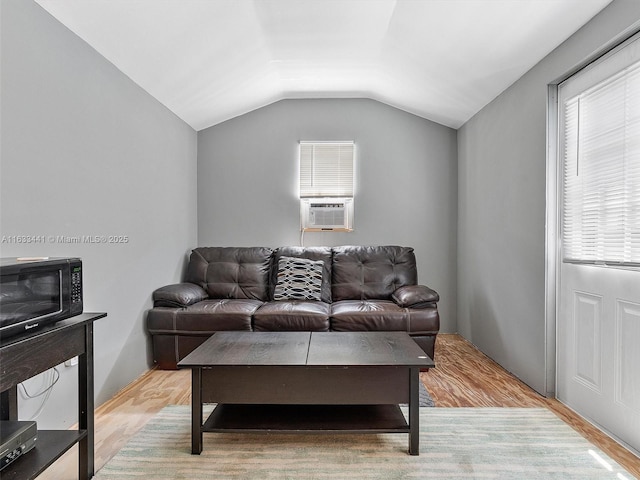 living room featuring cooling unit, vaulted ceiling, and light wood finished floors