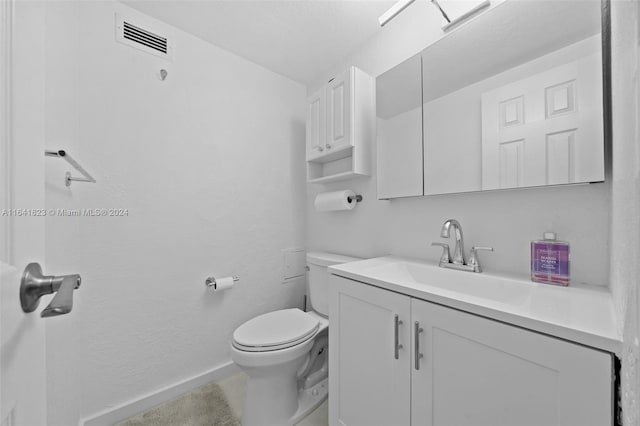 half bathroom featuring vanity, toilet, baseboards, and visible vents