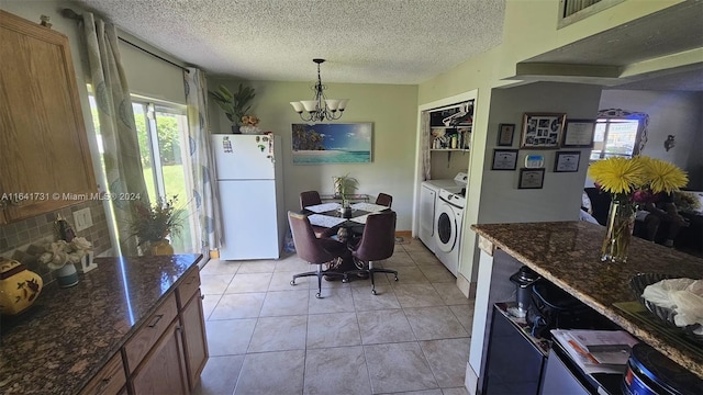 kitchen with a textured ceiling, light tile patterned floors, a notable chandelier, white refrigerator, and independent washer and dryer