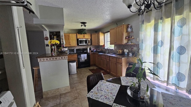 kitchen featuring a textured ceiling, light tile patterned floors, backsplash, a chandelier, and range