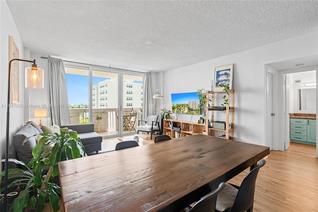 dining room featuring light hardwood / wood-style flooring, a textured ceiling, and a wall of windows