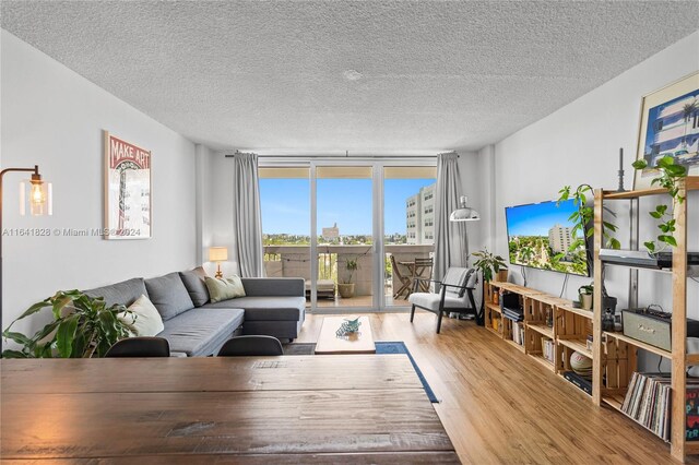 living room featuring light wood-type flooring, expansive windows, and a textured ceiling