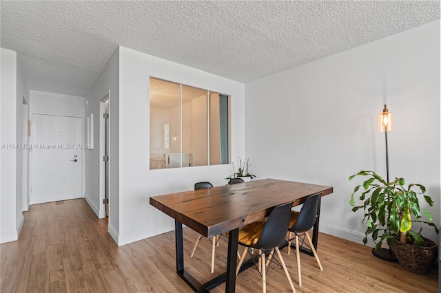 dining area with a textured ceiling and light hardwood / wood-style floors