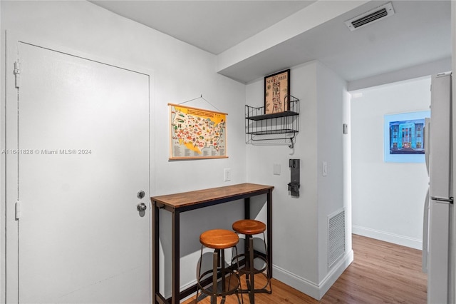 kitchen with wood counters, light wood-type flooring, a breakfast bar area, and white fridge