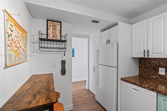 kitchen featuring light wood-type flooring, backsplash, white cabinetry, dark stone countertops, and white appliances