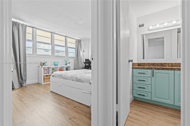 bedroom with light hardwood / wood-style floors and a textured ceiling