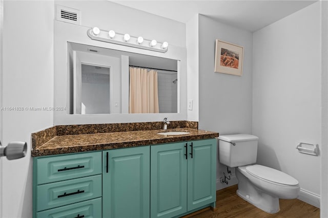 bathroom with wood-type flooring, toilet, vanity, and curtained shower