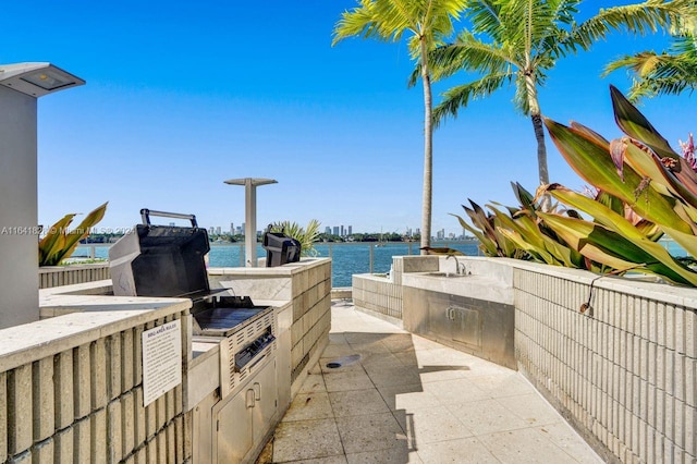 view of patio / terrace with sink, a water view, and area for grilling