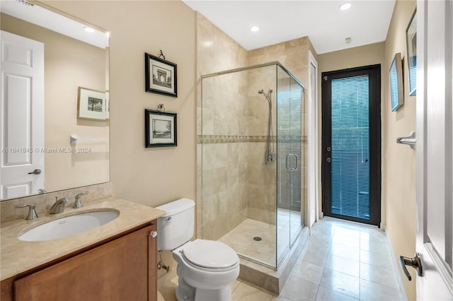 bathroom with a shower with door, vanity, tile patterned floors, and toilet