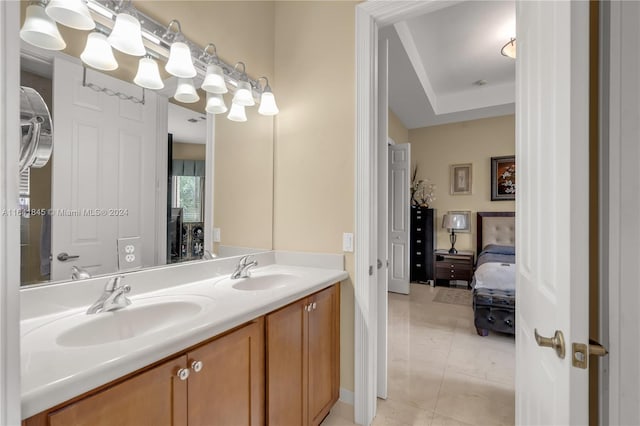 bathroom with dual bowl vanity, a tray ceiling, and tile patterned flooring