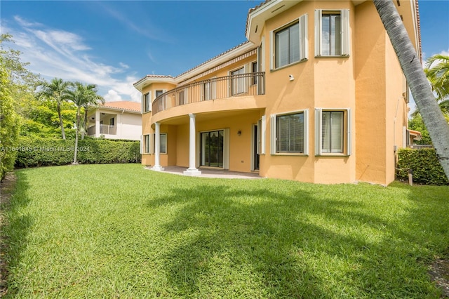 rear view of property with a balcony and a lawn