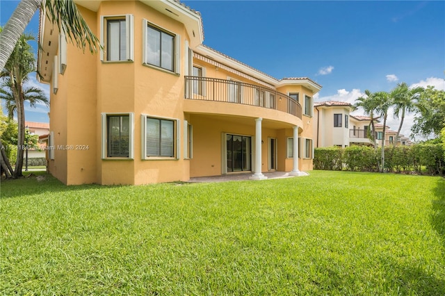 back of property featuring a balcony and a lawn