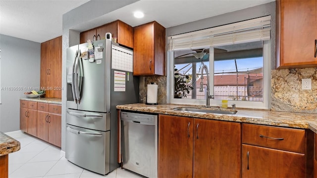 kitchen featuring backsplash, light stone counters, stainless steel appliances, and sink