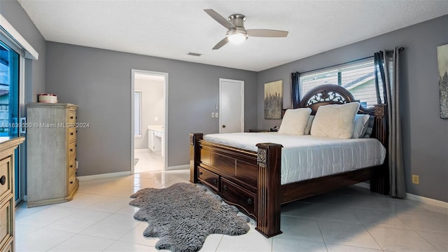 bedroom with ceiling fan, light tile patterned floors, connected bathroom, and a textured ceiling